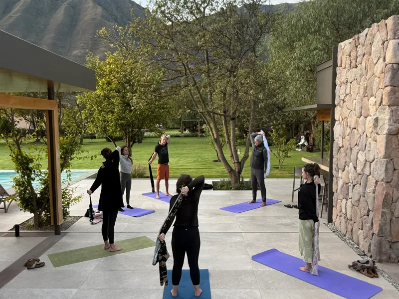 people practicing yoga outside the hot room with mountains in the background