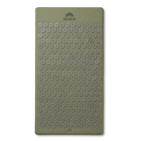 A green Shakti Mat used for acupressure and recovery after a hot yoga practice.