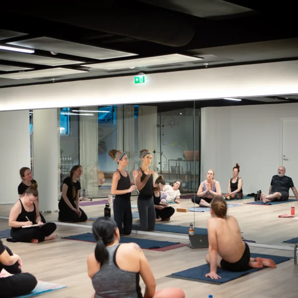 Jasmine leading a 26&2 yoga Q&A workshop session with students in a hot yoga studio.