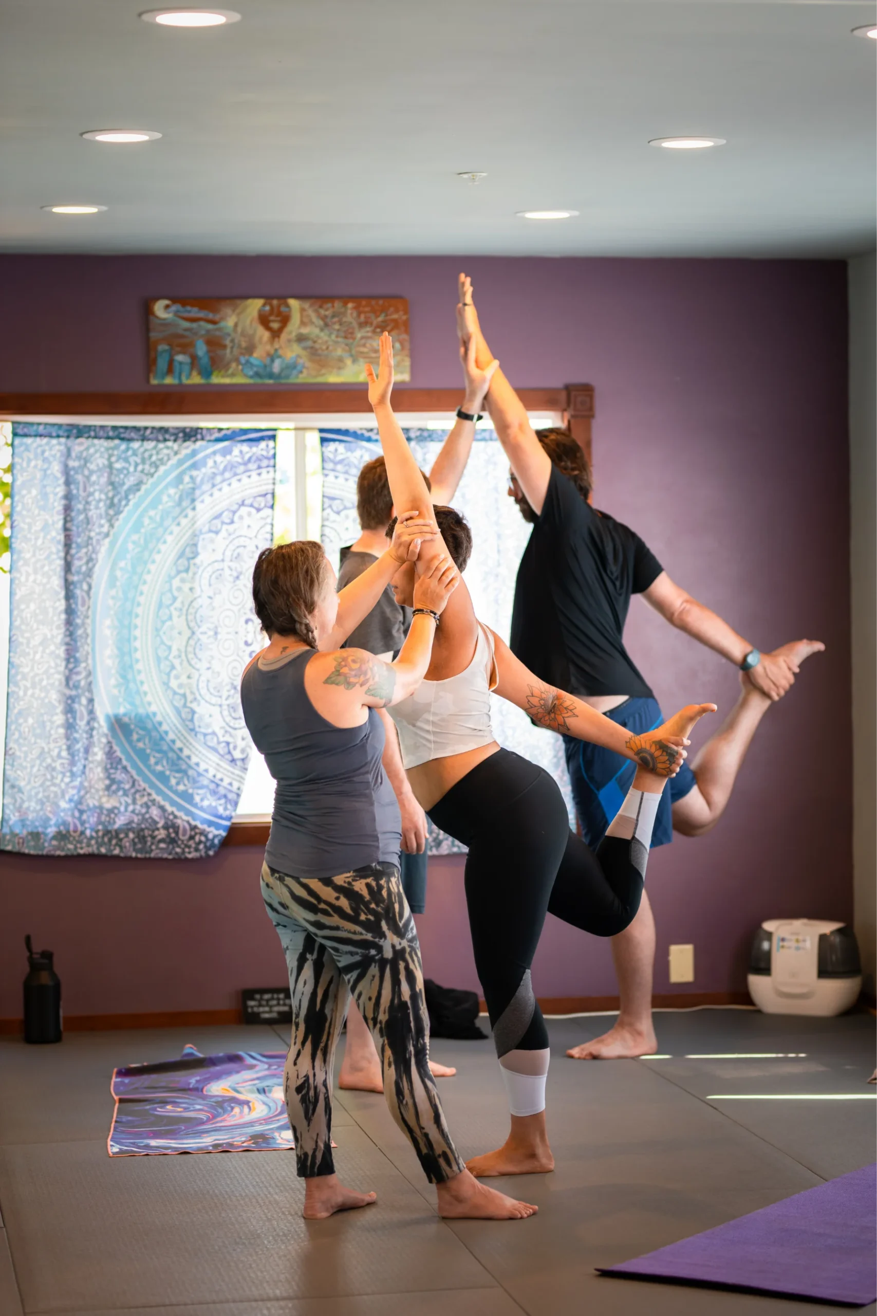 Instructor assisting a student with the Standing Bow Pulling pose.