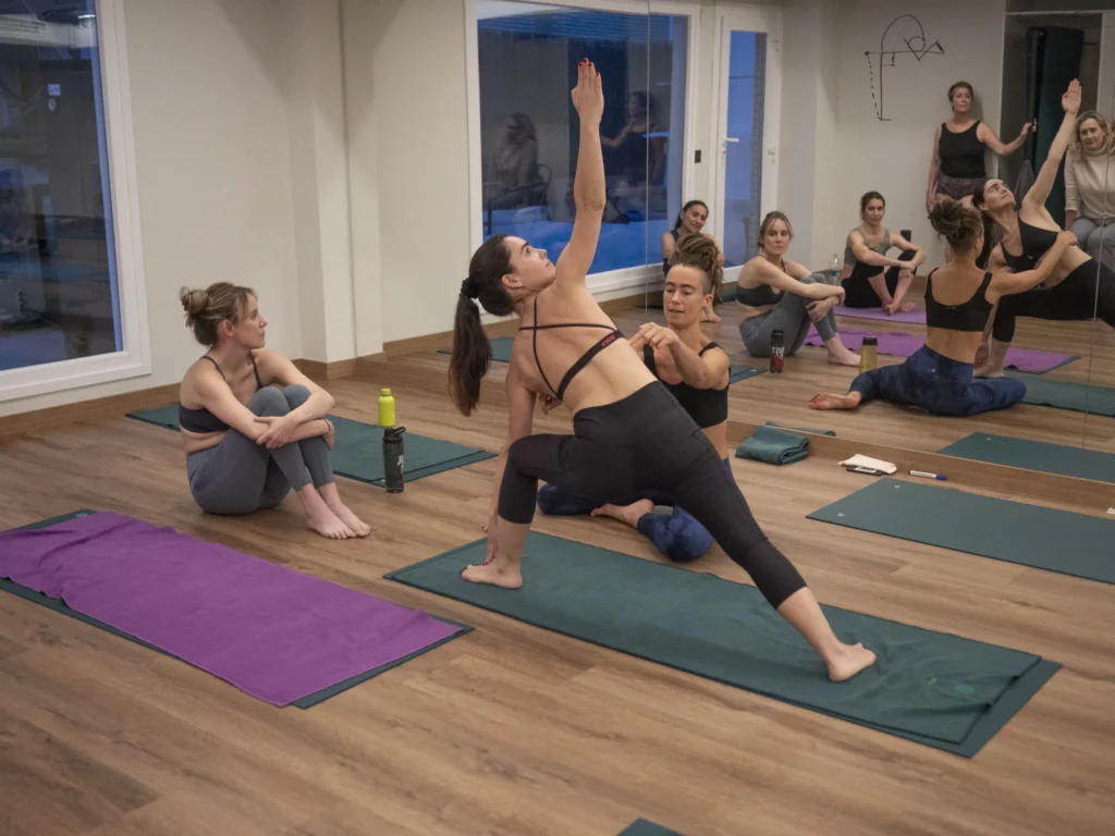 Instructor providing a hands-on technical adjustment for a student in Triangle pose.