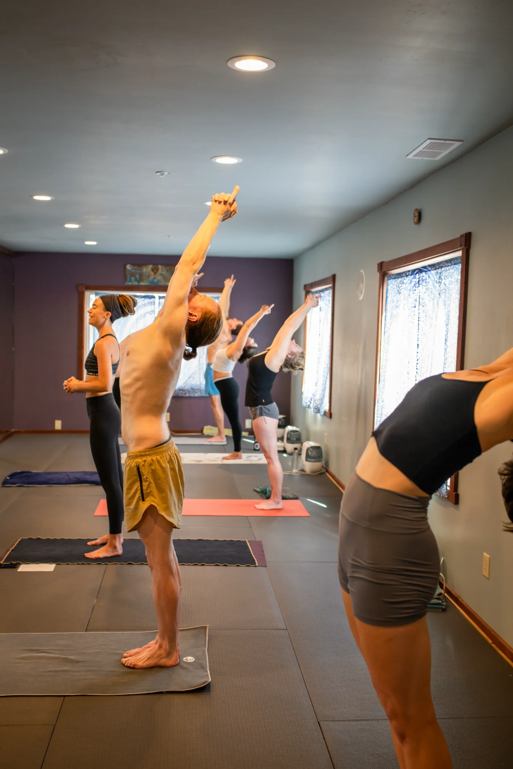 A row of students performing a standing backbend in a studio during structured yoga teacher trainings practice