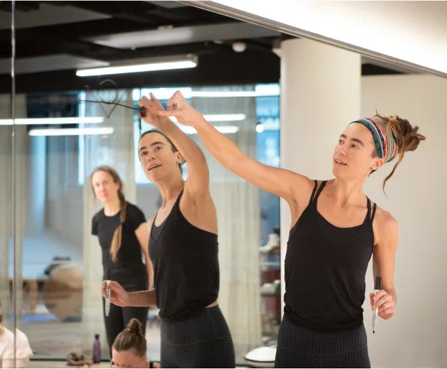 Close-up of Jasmine drawing posture alignment markers on a mirror.