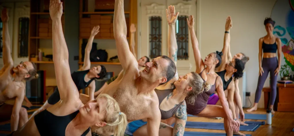 Group of smiling students practicing together in a bright studio during a beginners yoga retreat Portugal.