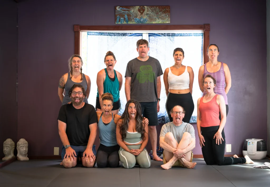 A group of students practicing the playful and expressive Lion’s Breath during a yoga teacher training session to build confidence and release tension.